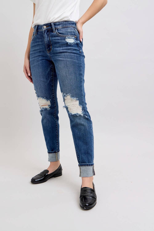 Person wearing distressed blue jeans on a white background