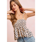 Woman wearing a polka dot top and jeans against a pink background