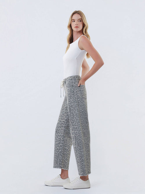 Woman wearing a white tank top and patterned pants on a white background