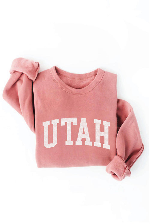 Pink sweatshirt with 'UTAH' printed on it against a white background