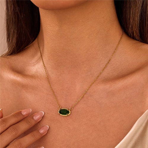 Gold necklace with a green pendant worn by a person