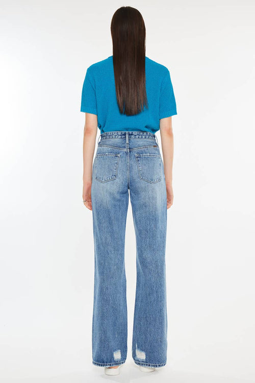 Person wearing a blue shirt and light blue jeans on a white background