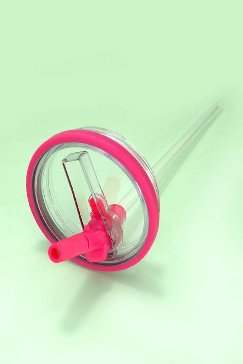Pink and clear straw with a small red object on a light green background
