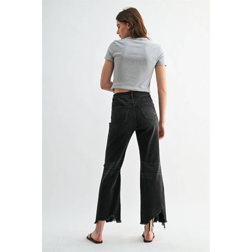 Woman wearing black flared jeans and a gray crop top on a white background