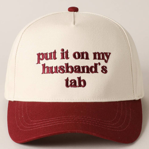 Cap with text 'put it on my husband's tab' on a plain background
