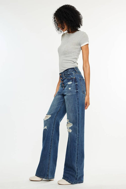 Person wearing a gray t-shirt and blue distressed wide-leg jeans on a white background