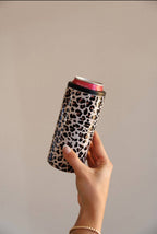 Hand holding a can with a leopard print sleeve against a plain background