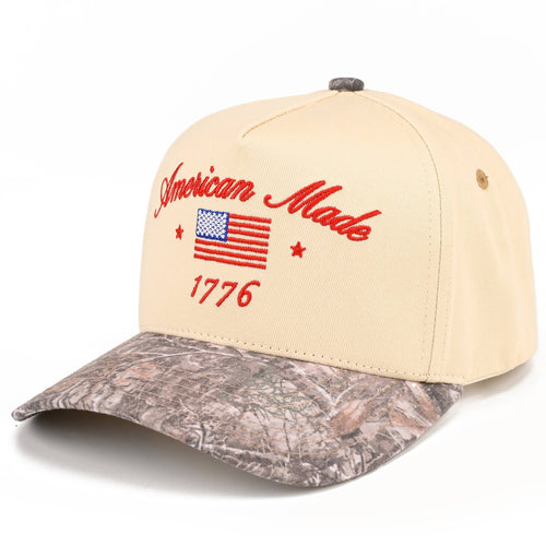 Beige cap with camouflage brim and 'American Made 1776' text on a white background