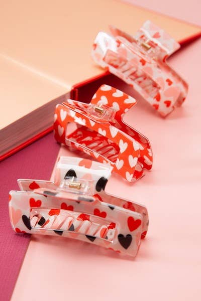 Set of heart-themed hair clips on a pink background