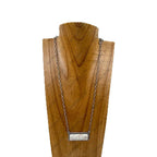 Necklace with a rectangular pendant on a wooden stand against a white background