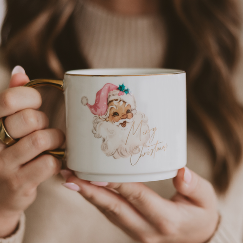 Person holding a Christmas-themed mug with a Santa Claus design.