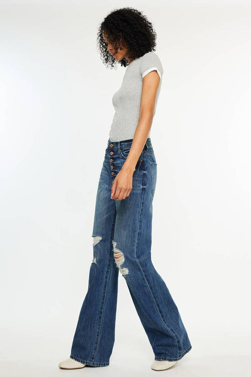 Woman wearing a gray t-shirt and blue flared jeans on a white background