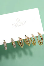 Set of gold hoop earrings on a Jocelyn Company card against a green background