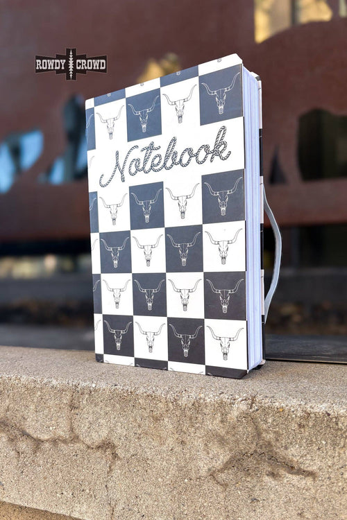 Notebook with checkered design and bull head pattern on a stone surface