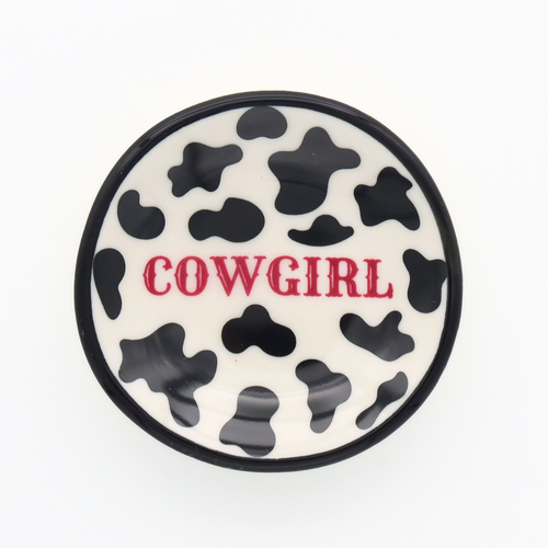 Round ceramic coaster with cow print and 'Cowgirl' text on a white background