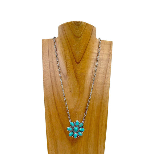 Necklace with a turquoise flower pendant on a wooden stand against a white background