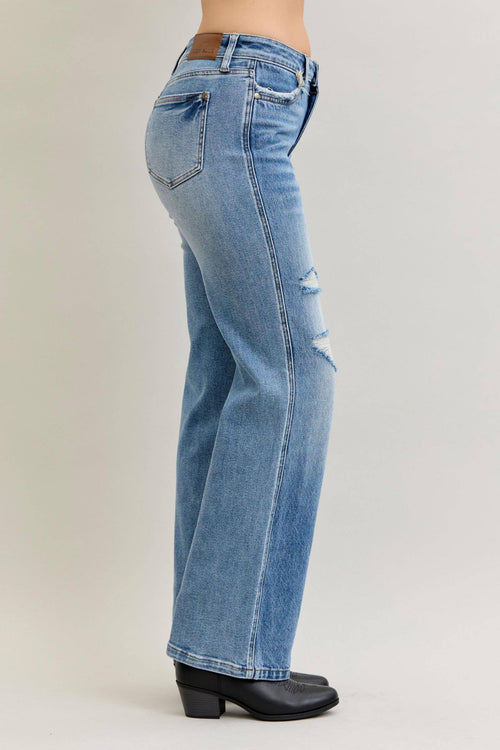 Blue jeans worn by a person on a plain background