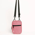 Pink crossbody bag with a black strap on a white background
