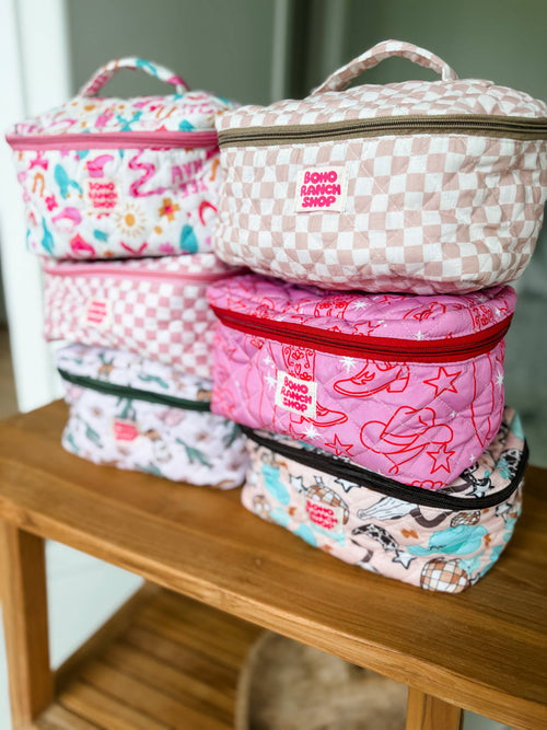 Stack of colorful makeup bags on a wooden surface