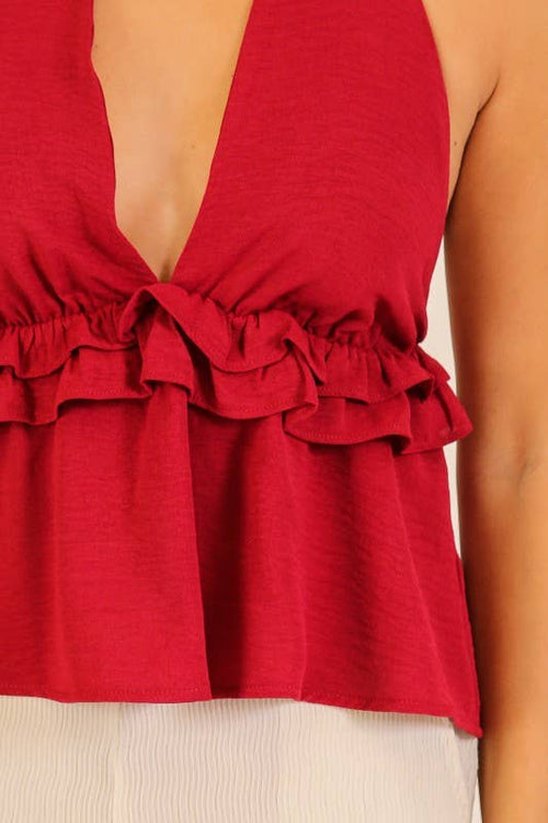 Red ruffled top worn by a person on a neutral background
