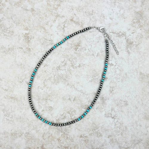 Necklace with black and turquoise beads on a light gray surface