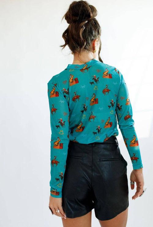 Person wearing a turquoise sweater with horse patterns on a white background