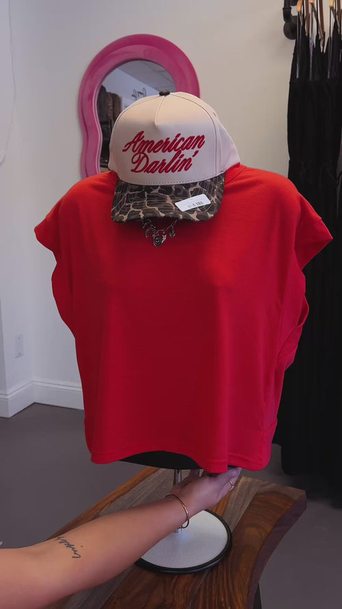 Red shirt on a mannequin with a hat and necklace being spun around. 